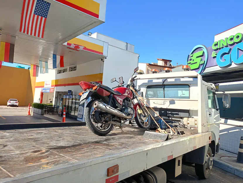 Motocicleta vermelha presa por cintas sobre a plataforma do guincho.