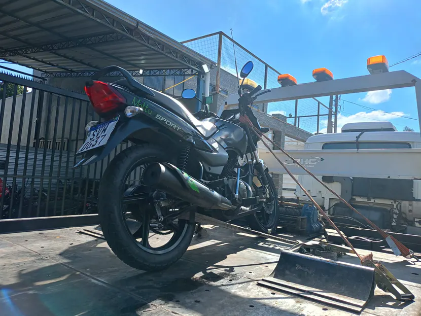 Motocicleta preta presa por cintas sobre a plataforma, vista por trás.