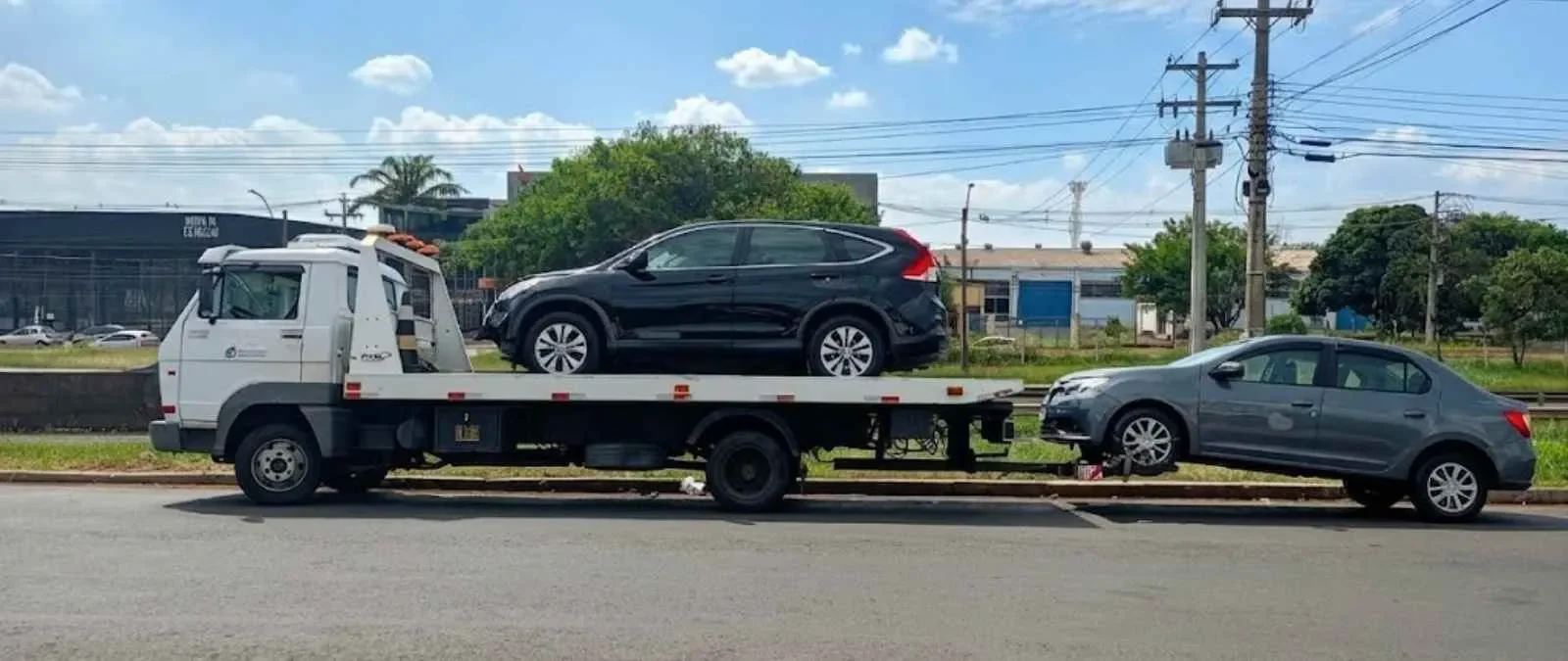 SUV escuro sobre a plataforma de um caminhão de guincho.