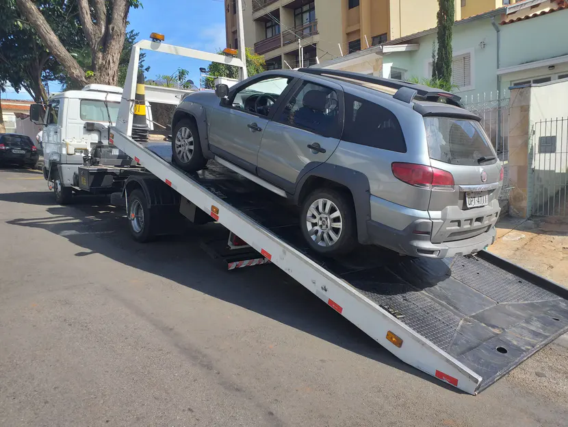 SUV prata sobre a plataforma inclinada de um caminhão de guincho.