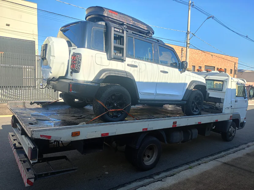 SUV branco com bagageiro sobre a plataforma do caminhão.