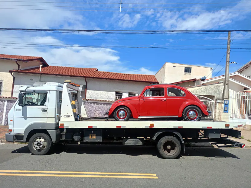 Fusca vermelho sobre a plataforma de um caminhão de guincho.