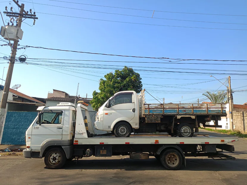 Caminhão leve de carroceria aberta sobre a plataforma do guincho.