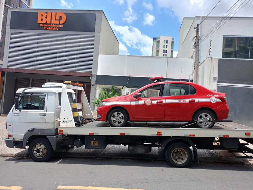 Sedã vermelho sobre a plataforma do caminhão em uma rua.