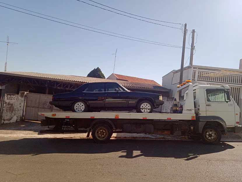 Sedã escuro antigo sobre a plataforma de um caminhão de guincho.