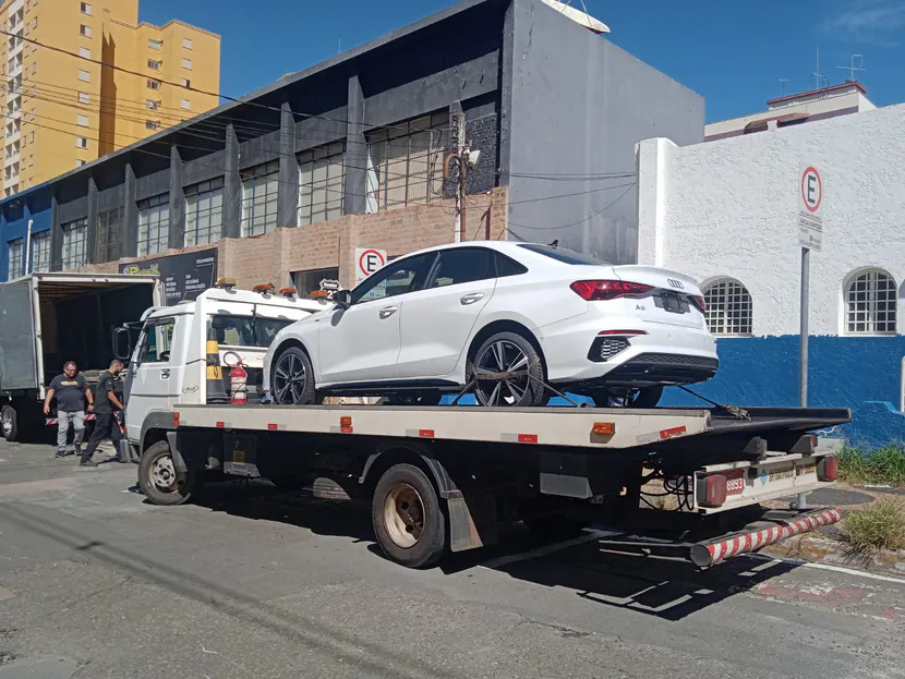 SUV branco sobre a plataforma do guincho em uma rua.