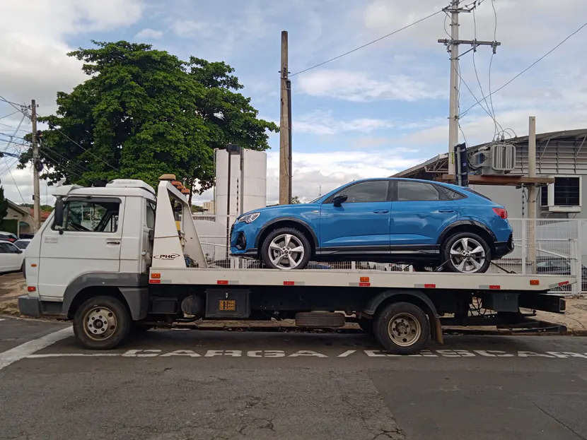 SUV azul sobre a plataforma de um caminhão de guincho.