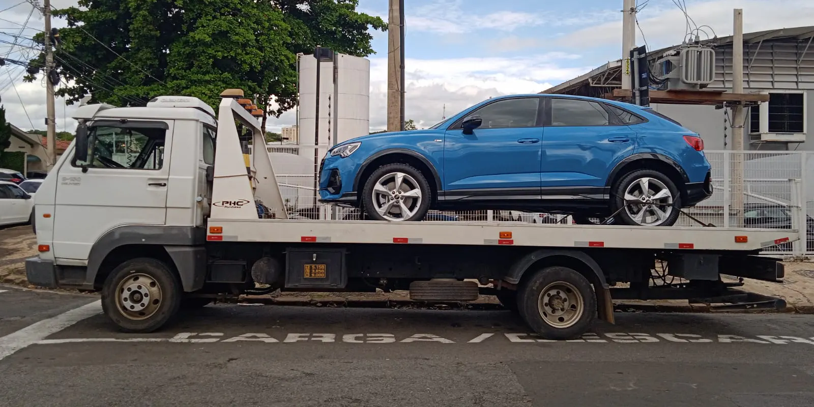 SUV azul sobre a plataforma de um caminhão de guincho.
