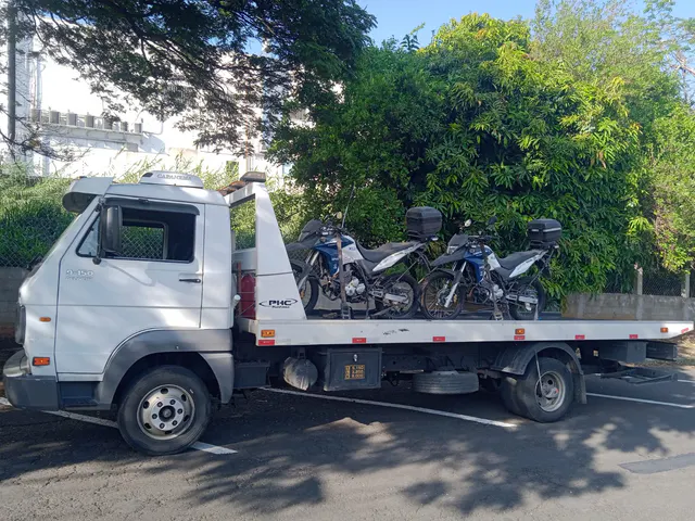 Duas motocicletas com baús presas à plataforma, vistas próximas à cabine.