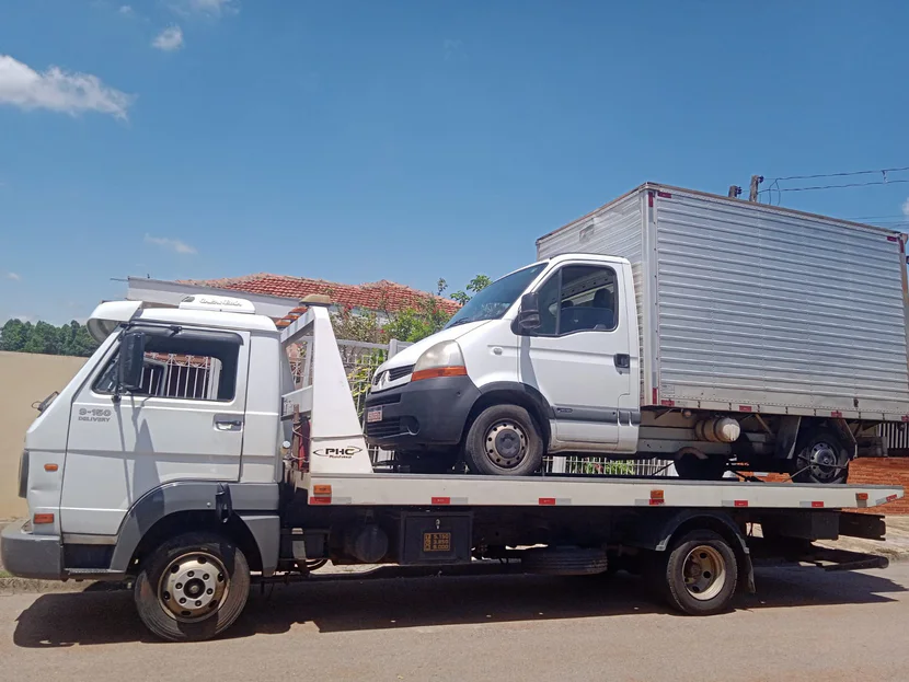 Utilitário com baú sobre a plataforma do caminhão sob céu azul.